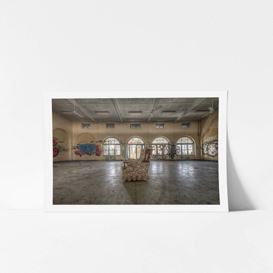 Side Chair at Waterfall Sanatorium, a floral armchair sits alone at the centre of a large hall.
