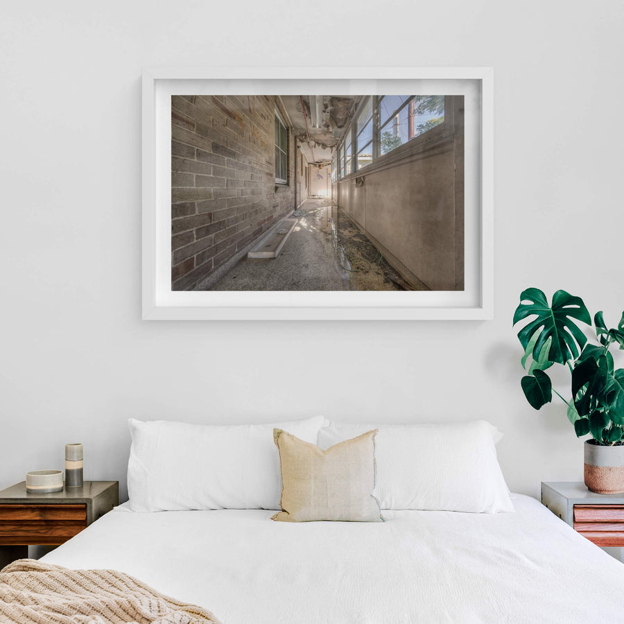 Side Hall at Waterfall Sanatorium, a narrow enclosed corridor runs between a brick wall and a bank of steel-framed windows.