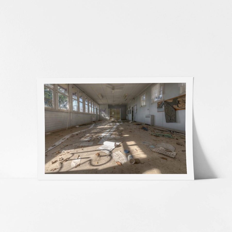 Sprawl at Waterfall Sanatorium, sunlight falls through a long bank of windows onto a debris-covered floor.