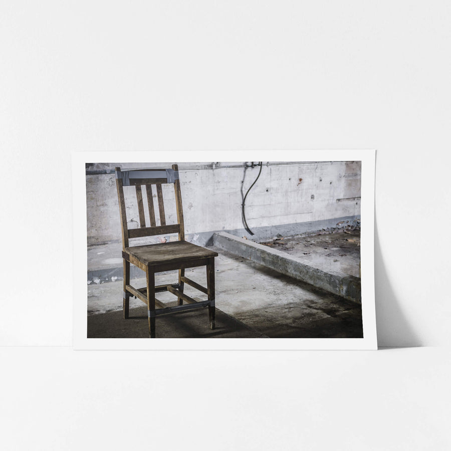 Chair at West Ryde Pumping Station, a wooden chair sits on a bare concrete floor, held together with strips of grey duct.