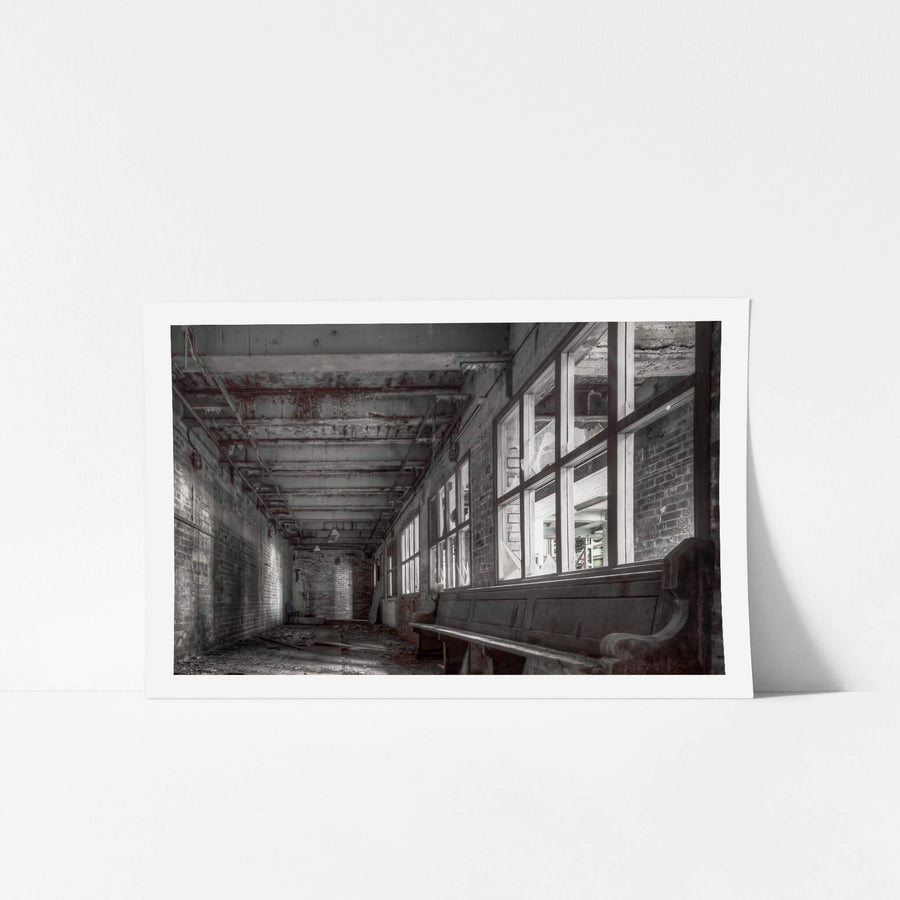 Lunch Room at White Bay Power Station, a timber church pew sits against a wall of broken windows in a narrow brick corridor.